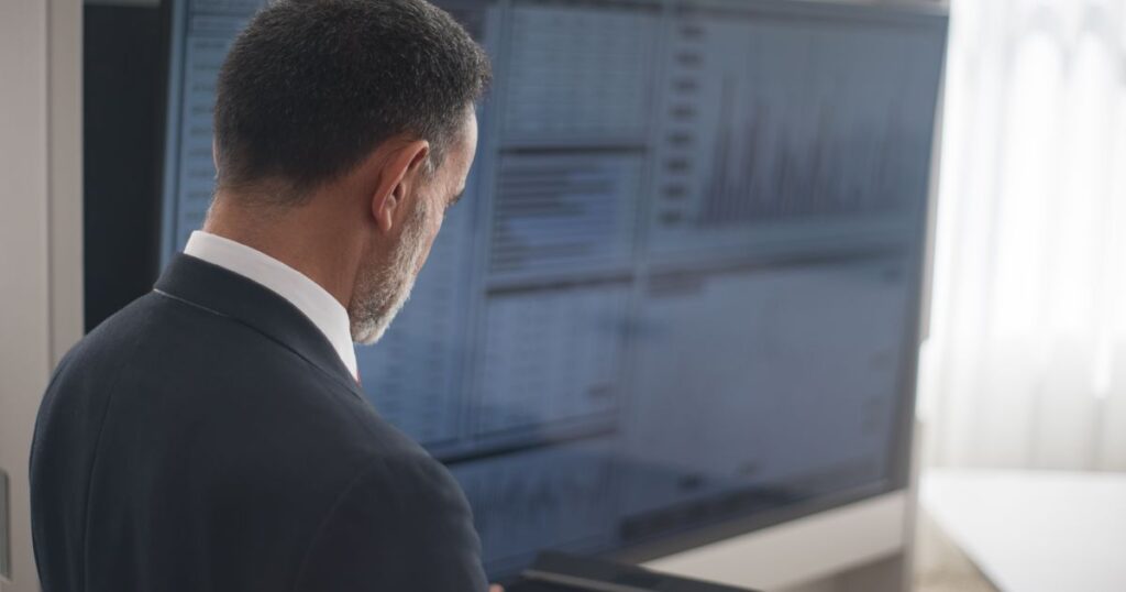 Professionista in giacca analizza dati su un ampio schermo in ufficio — AI Act, il regolamento europeo sull'intelligenza artificiale per le PMI